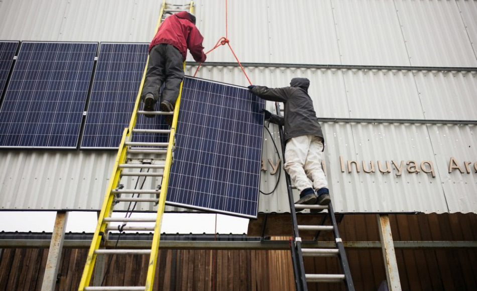 Der Ingenieur Duncan Martin (links) von Vancouver Renewable Energy Coop und der Logistik-Koordinator von Greenpeace Canada, Claude Beausjour, installieren Solarpanels an der Fassade des Gemeindezentrums von Clyde River. Bild: Greenpeace